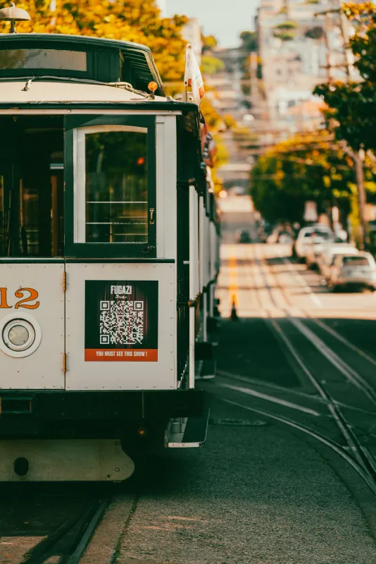 San Francisco cable car number 12 descending a steep street lined with parked cars