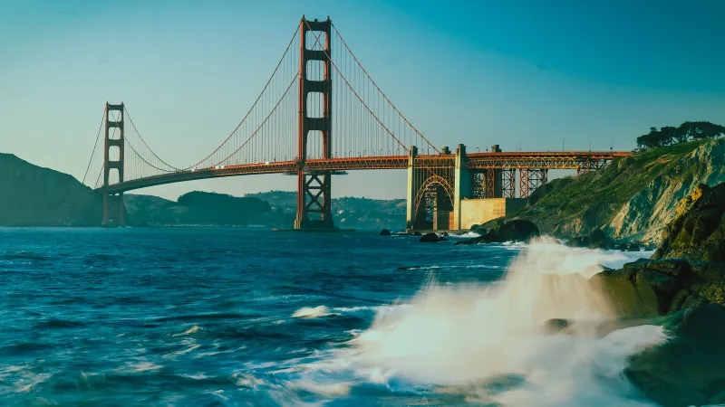 Golden Gate Bridge spanning the bay with turquoise water and waves breaking on rocks