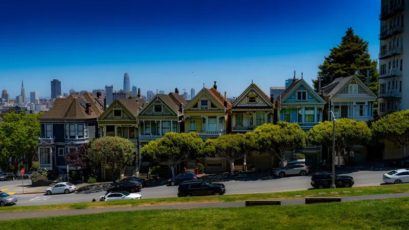 Row of Victorian houses at Alamo Square with the San Francisco skyline behind them