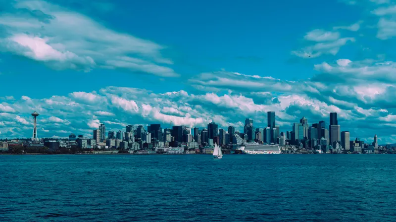 Seattle skyline with the Space Needle seen across the water under scattered clouds