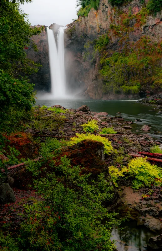 Snoqualmie Falls plunging into a misty pool with lush greenery in the foreground